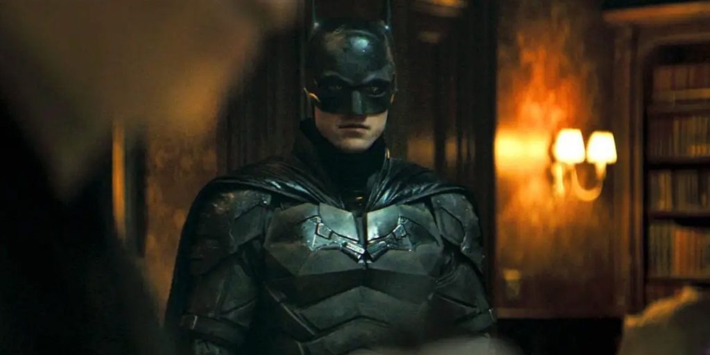 Batman standing in a dimly lit, antiquated room.
