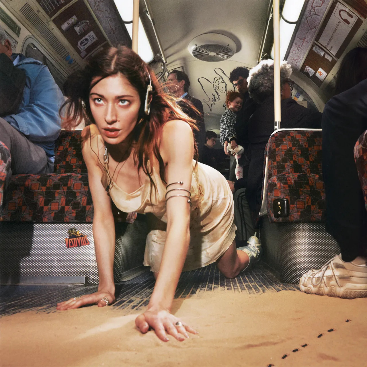 The album cover for singer Caroline Polachek's album "Desire, I Want To Turn Into You," which shows her crawling on the floor of a subway car into a pile of sand